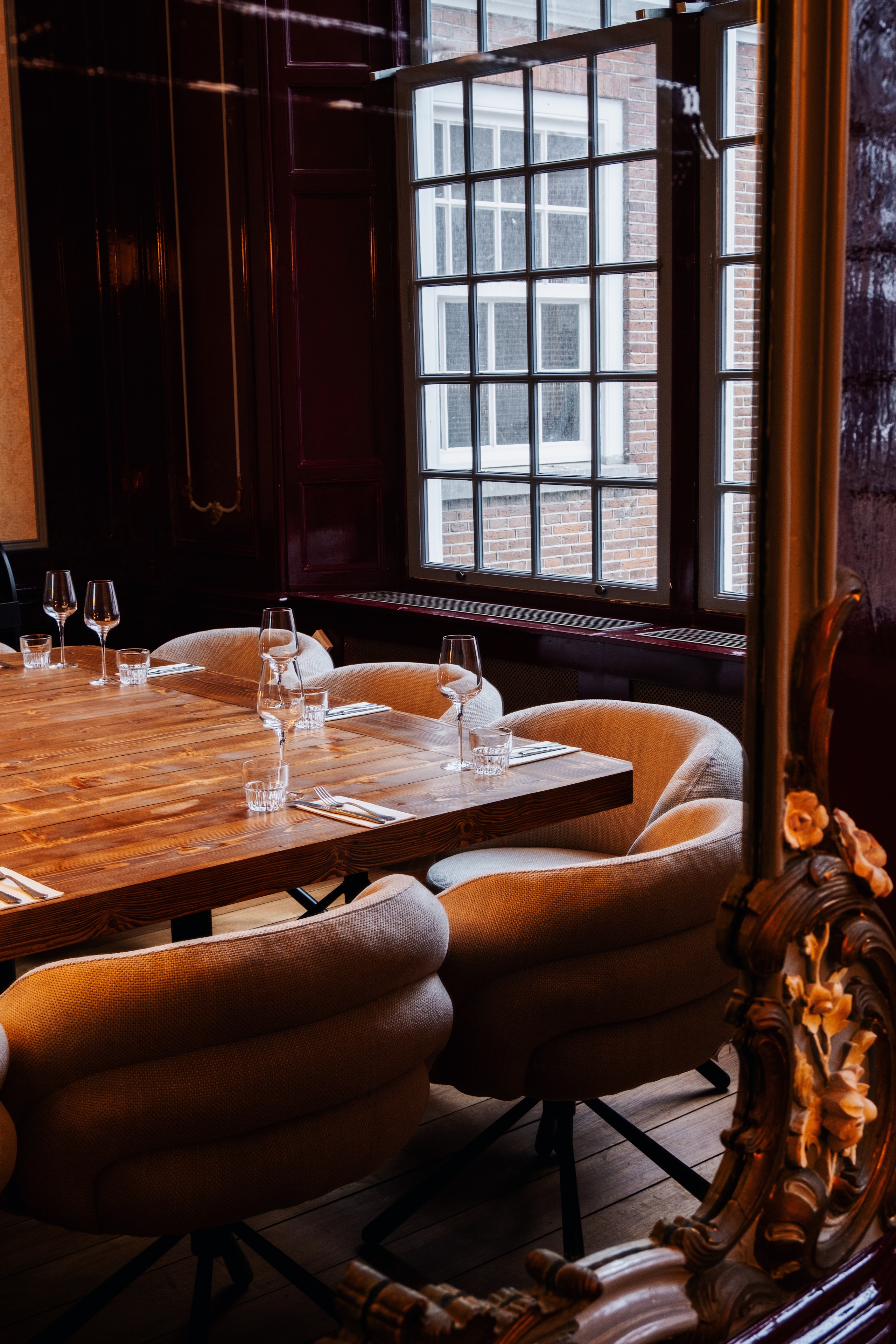 Gezellige eetkamer met houten tafel, beige stoelen, glazen en bestek, omgeven door warme houten panelen.