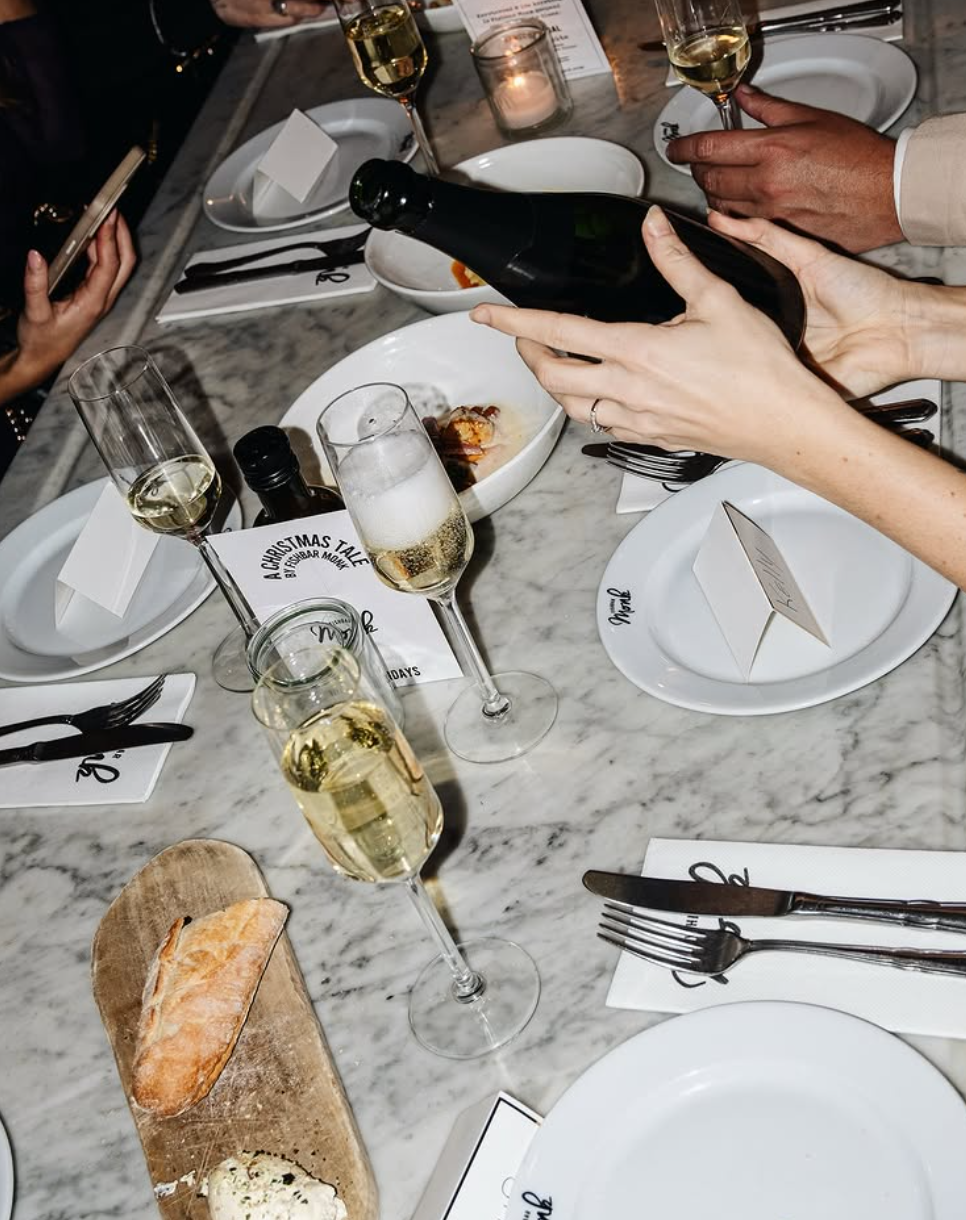 Gezellig gedekte marmeren tafel met champagneglazen, broodplank met kruidenboter en kaarslicht.