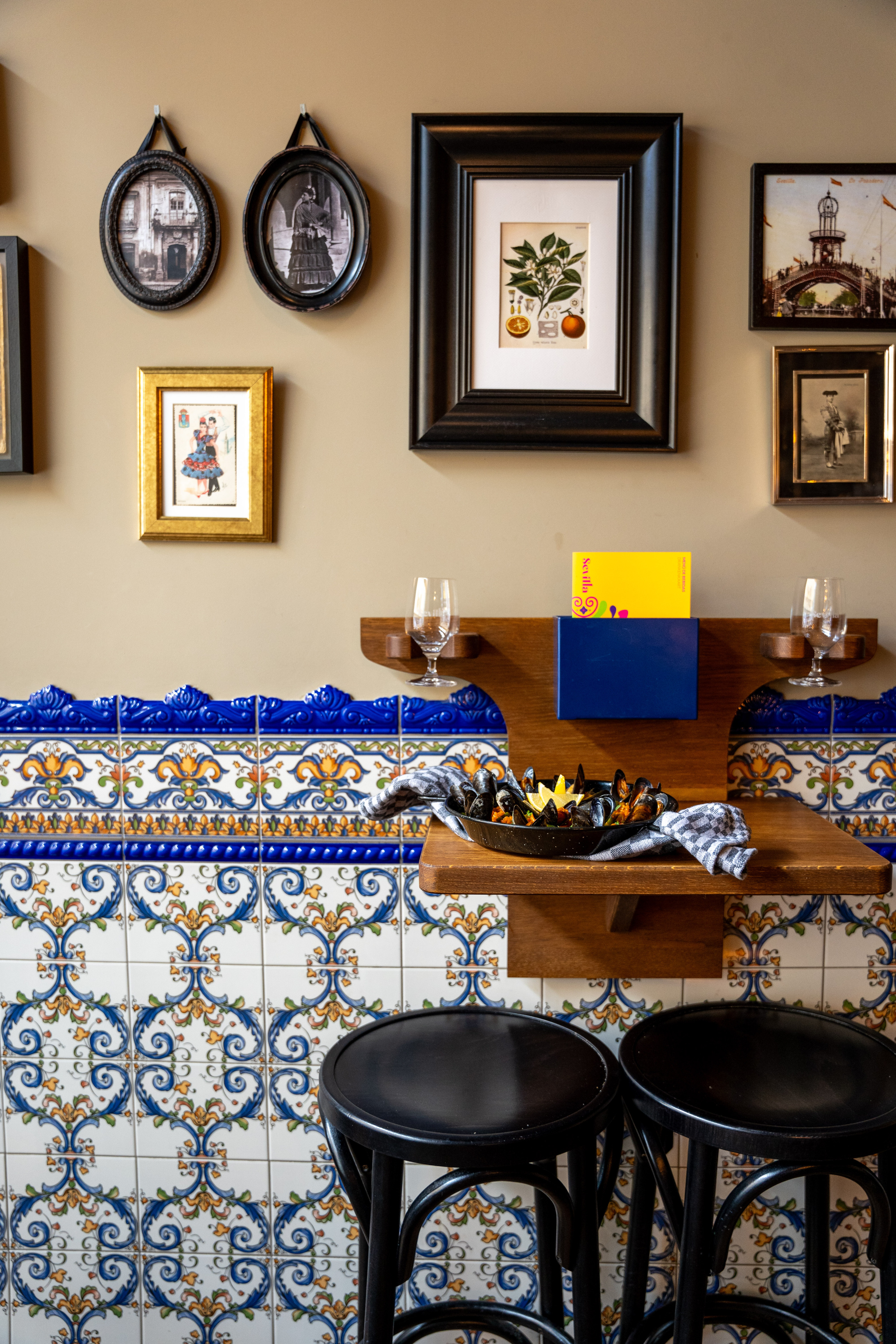 Mosselen in een zwarte schaal op houten tafel, omgeven door kleurrijke tegels en decoratieve lijsten.