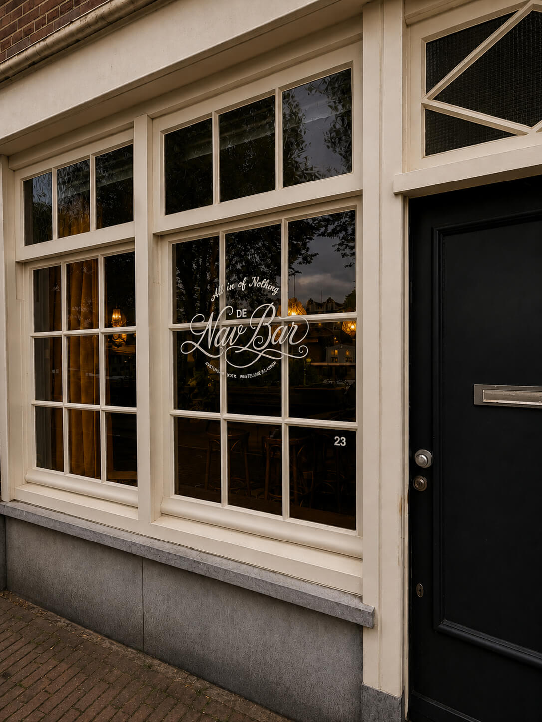 Witte houten gevel met grote ramen, weerspiegeling van bomen en binnenin warme verlichting.