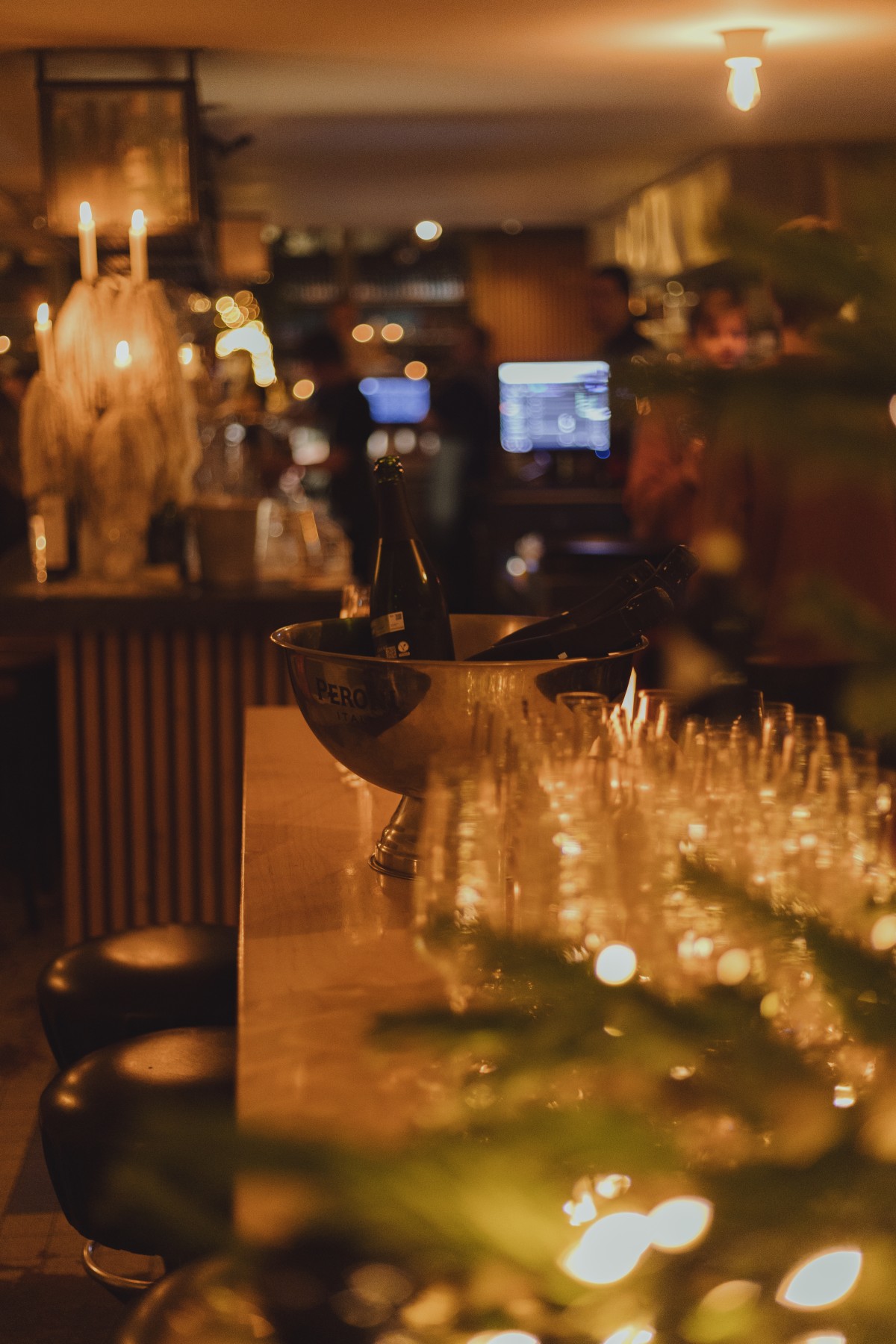 Gezellige bar met warme verlichting, champagnekoeler met flessen, glazen op de toog, sfeervolle avondsetting.